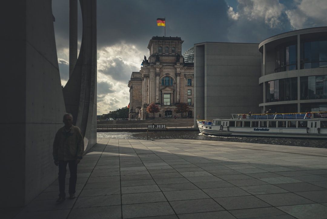 Reichstagsgebäude in Berlin mit deutscher Flagge und Person im Vordergrund, symbolisiert Reisen und Lieferung.